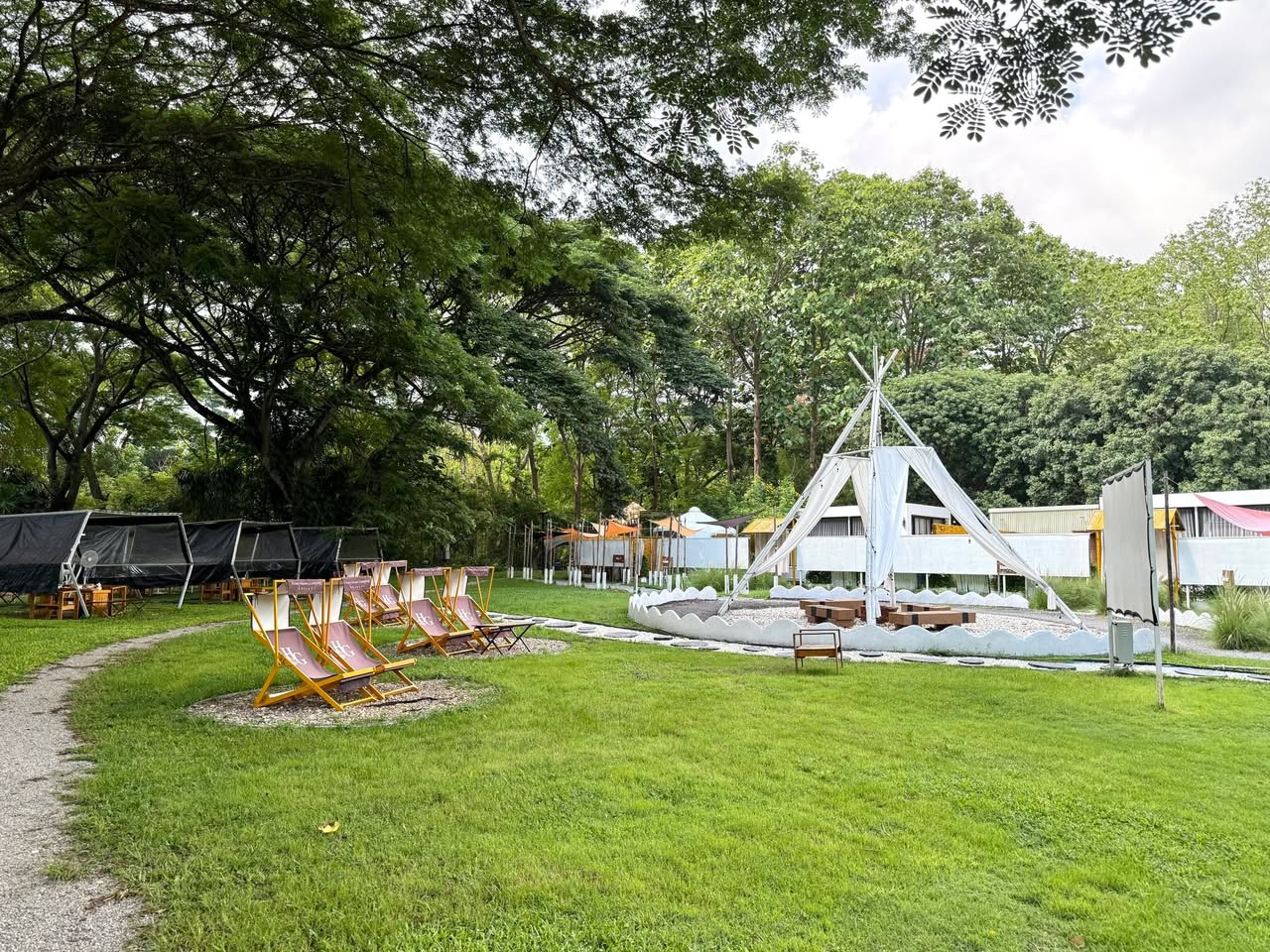 พื้นที่ส่วนกลางและลานสนามหญ้ากว้างขวางของ Honeymoon Glamping Khaoyai พร้อมเก้าอี้ผ้าใบและซุ้มกระโจม
