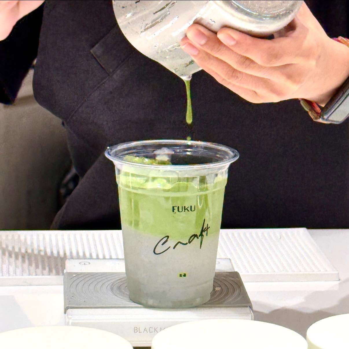 การเทมัทฉะชงสดลงในแก้วเครื่องดื่มเย็นใสที่ร้าน FUKU Craft